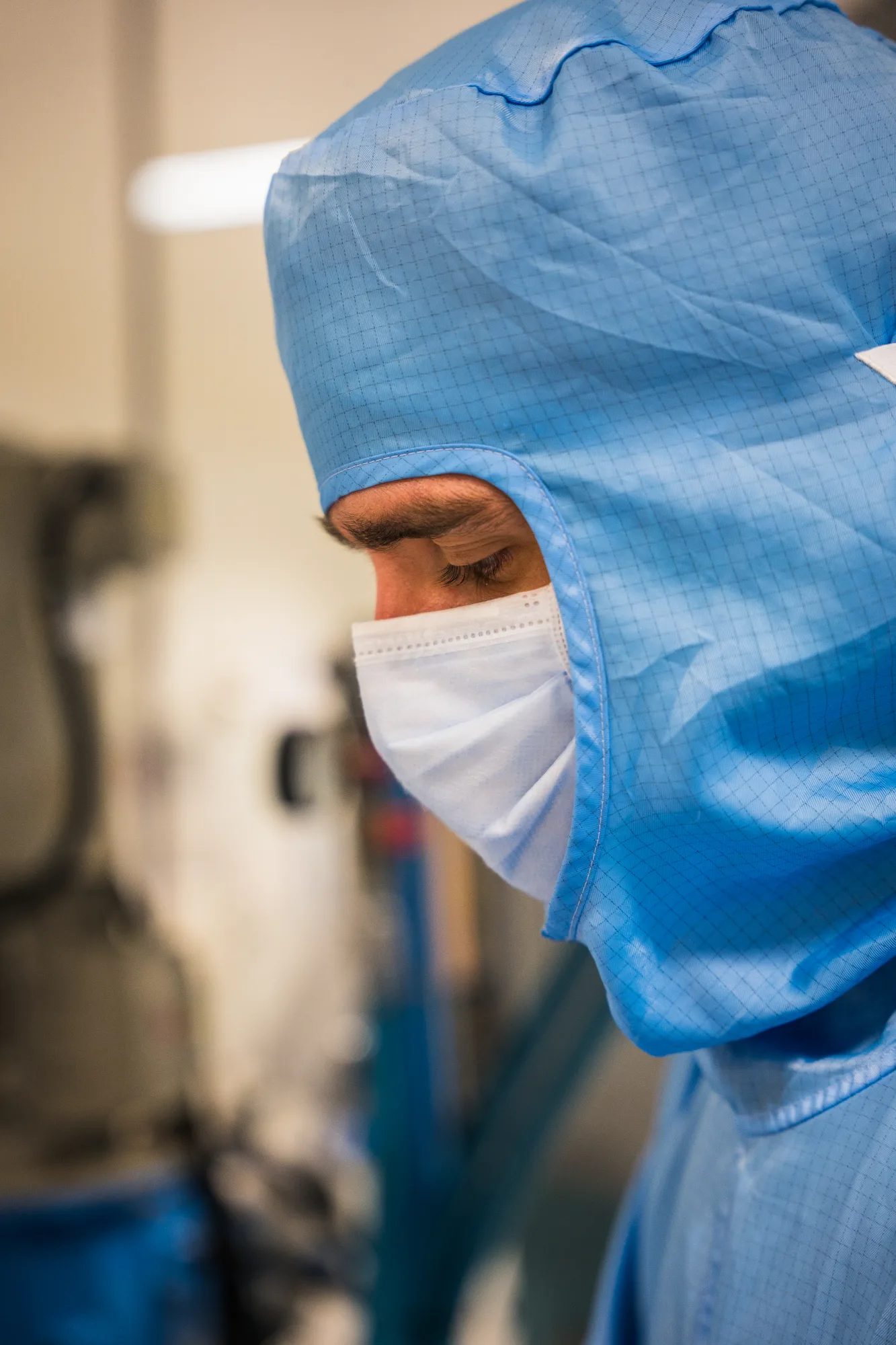 Cleanroom operator in blue antistatic gown and certified mask.
